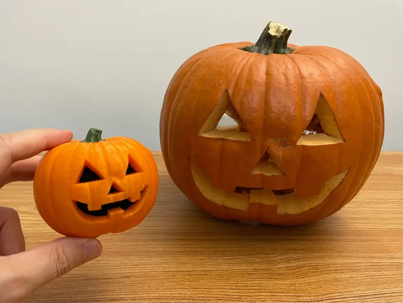 Original carved pumpkin next to a four-color 3D printed miniature created from a scan