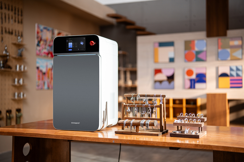 SnowPod desktop metal 3D printer displayed with metal jewelry samples