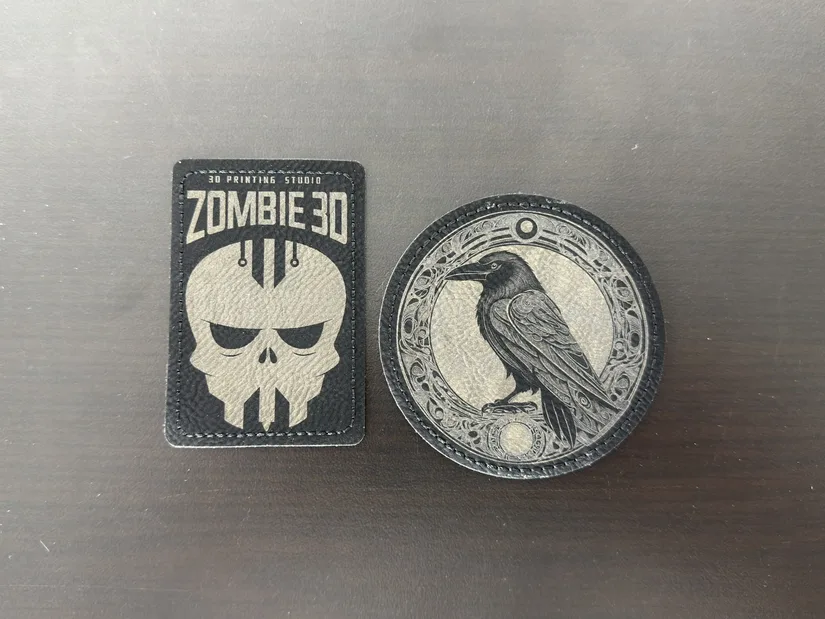 Two colour-change leather patches engraved with studio logo and raven artwork
