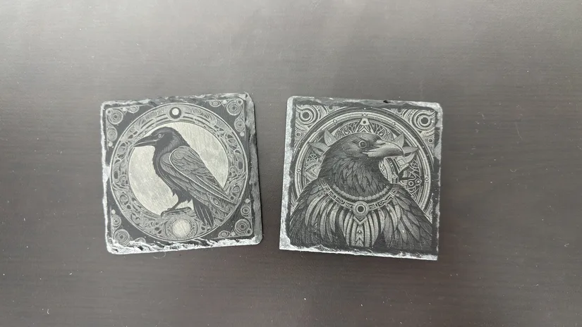 Two slate coasters with raven designs engraved by the xTool M2