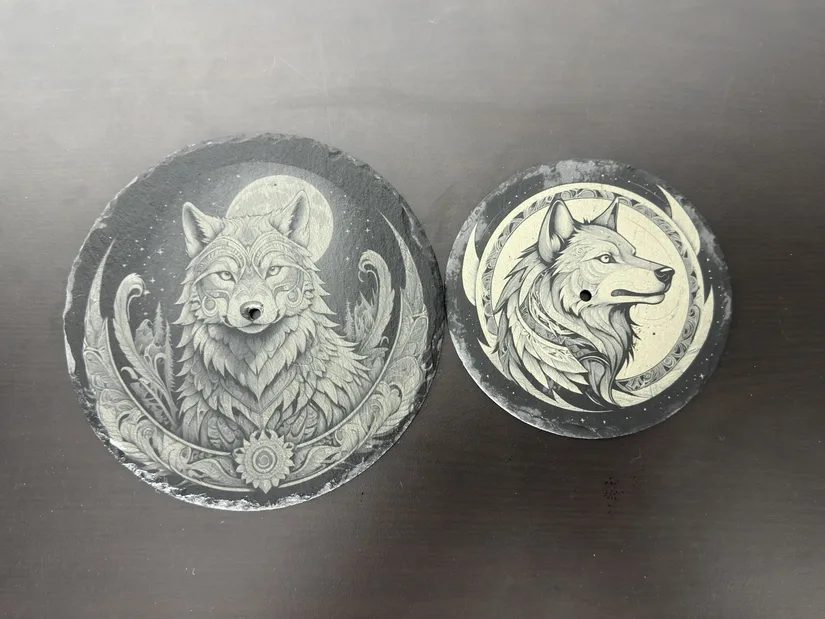 Wolf designs engraved on round slate pieces with the xTool M2